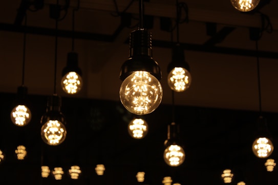 Several decorative light bulbs hanging from the ceiling, emitting a warm glow. The bulbs are evenly spaced and create a pattern of light across a dimly lit background.