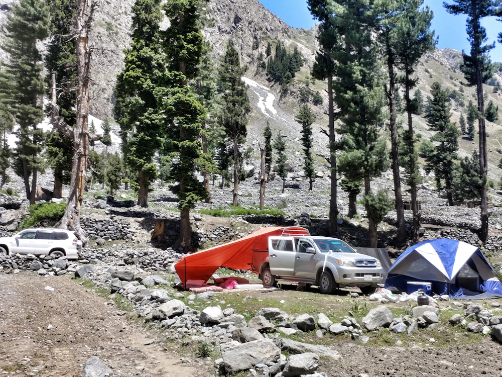 white and orange tent near green trees during daytime