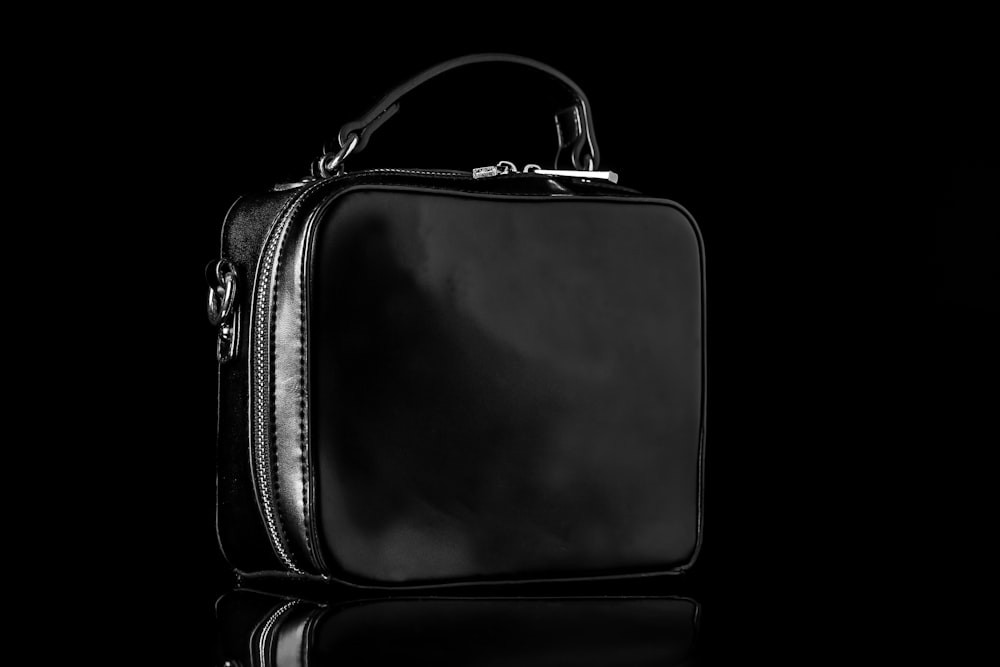 black leather sling bag on white background