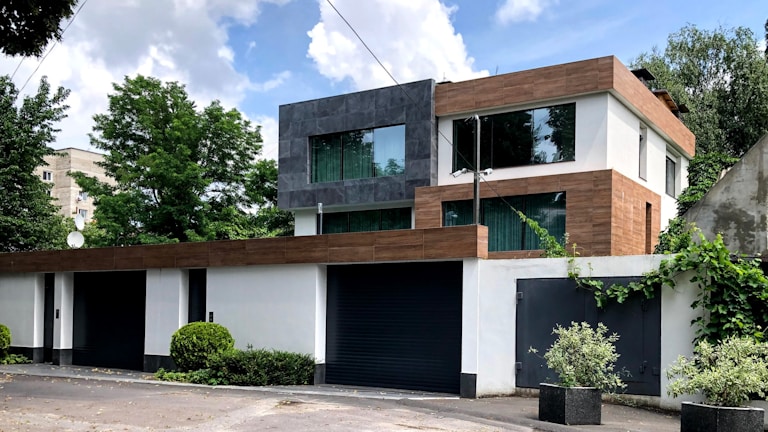A modern container home with large glass windows and a steel gray exterior under soft natural light.