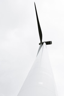 Close-up of a wind turbine blade with a backdrop of a bright, cloudy sky.