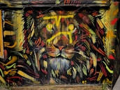 A vibrant graffiti artwork of a lion's face covers a wooden surface. The lion's eyes shine with bright yellow and its mane is an eclectic mix of vivid reds, oranges, yellows, and black. The dynamic strokes and colorful patterns create an intense and energetic visual impact.