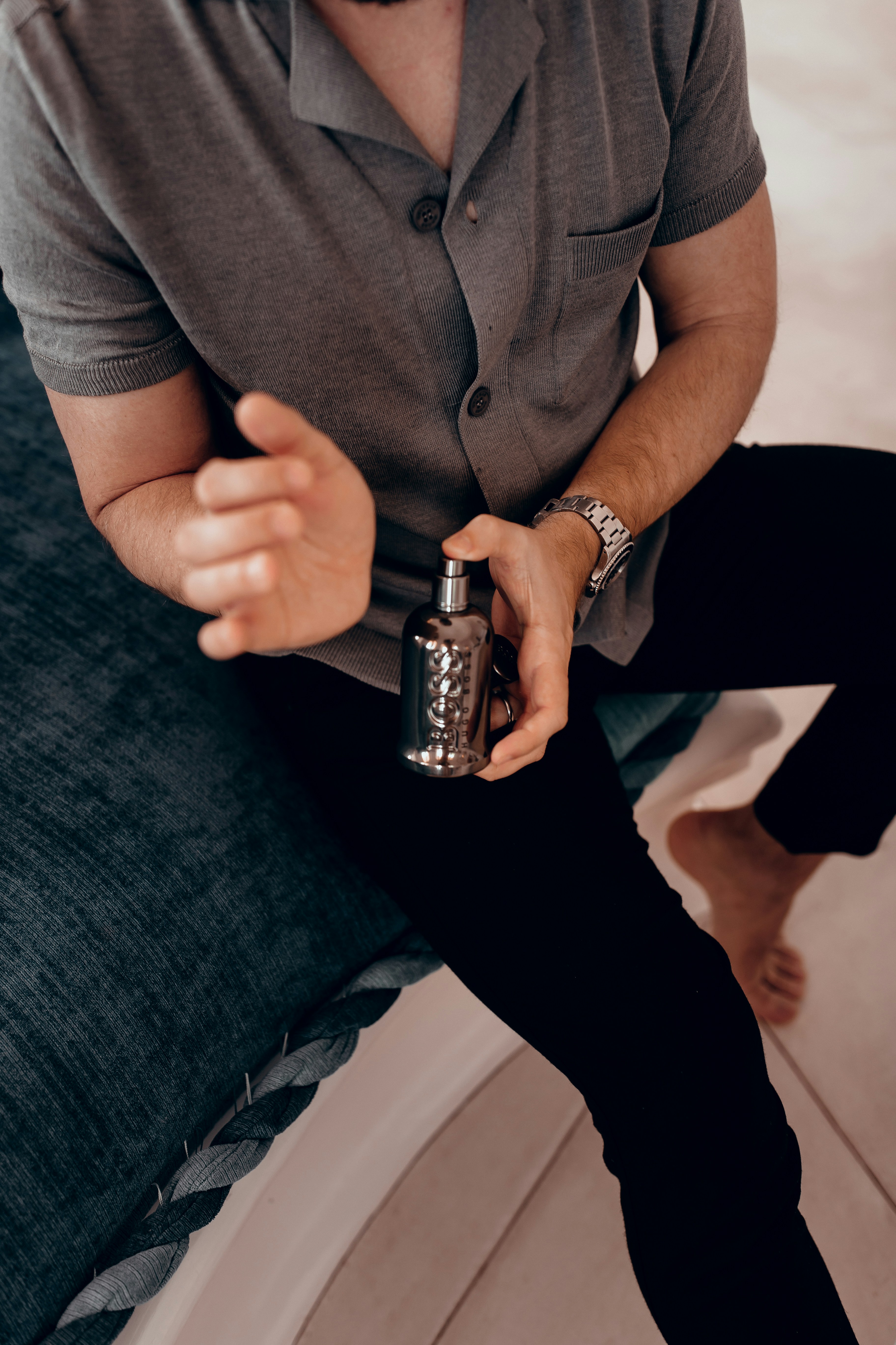 person in gray polo shirt holding silver can