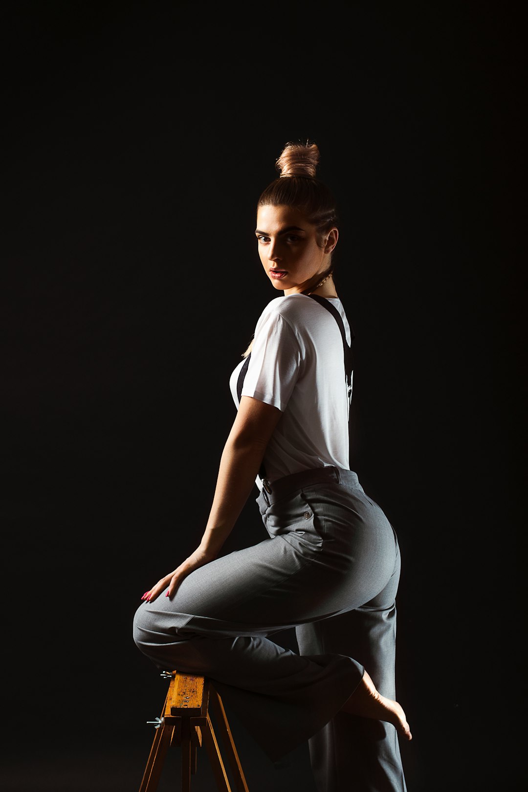 woman in white t-shirt and black pants sitting on black floor