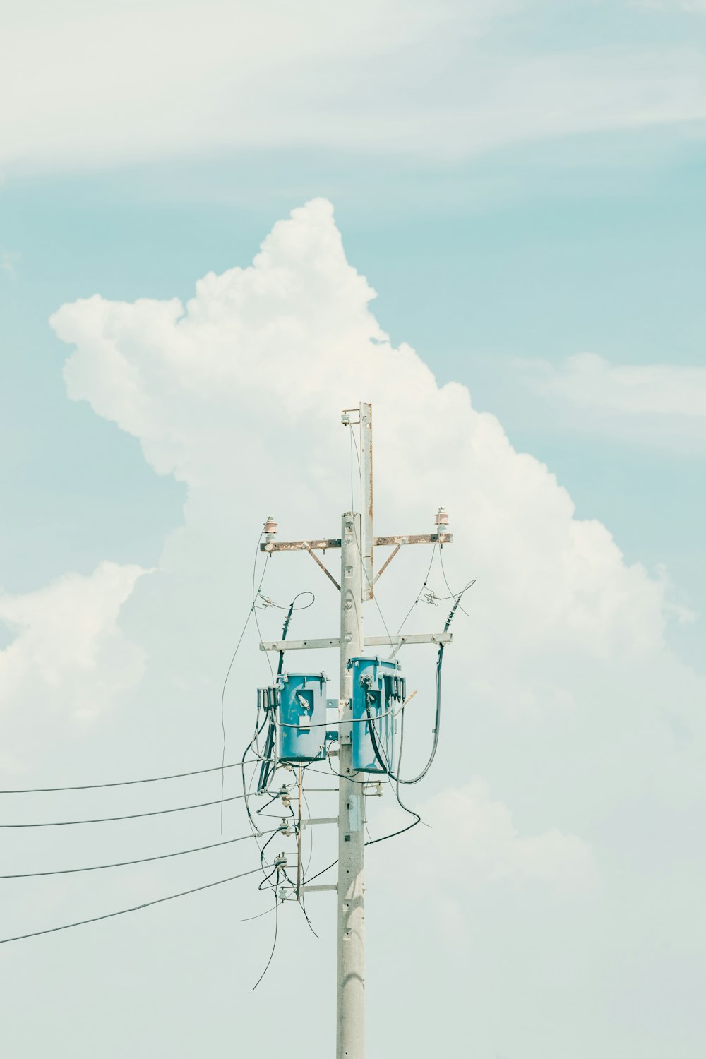 white and blue electric tower under white clouds