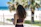 A young Thai woman browsing property listings on a smartphone with a beach background in Trat.
