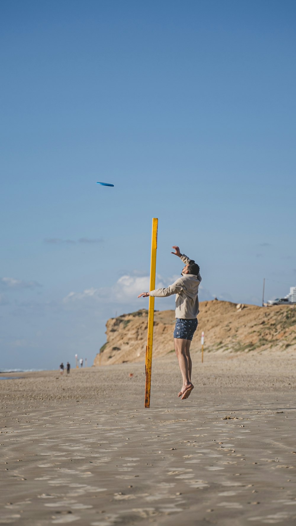 man in blue denim shorts and black shirt standing on brown sand during daytime