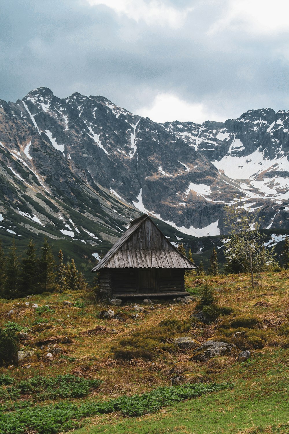 brown wooden house near snow covered mountain during daytime