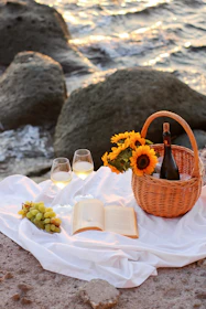 Close-up of a beautifully arranged picnic basket with fresh fruits and sparkling wine by the ocean.