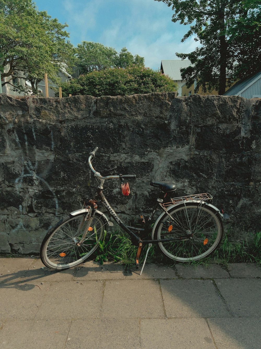 black and red city bike parked beside gray concrete wall during daytime