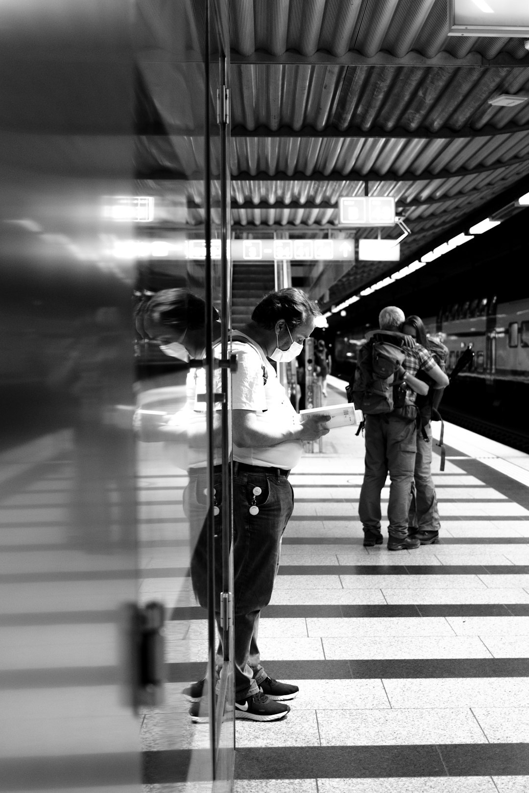 grayscale photo of man in white shirt and black pants standing on sidewalk