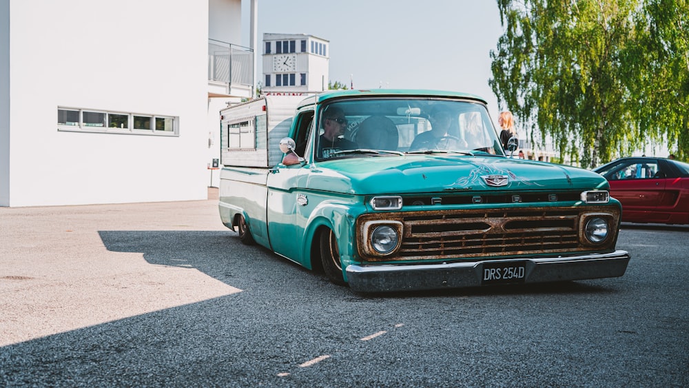 teal and white chevrolet single cab pickup truck parked on gray concrete road during daytime