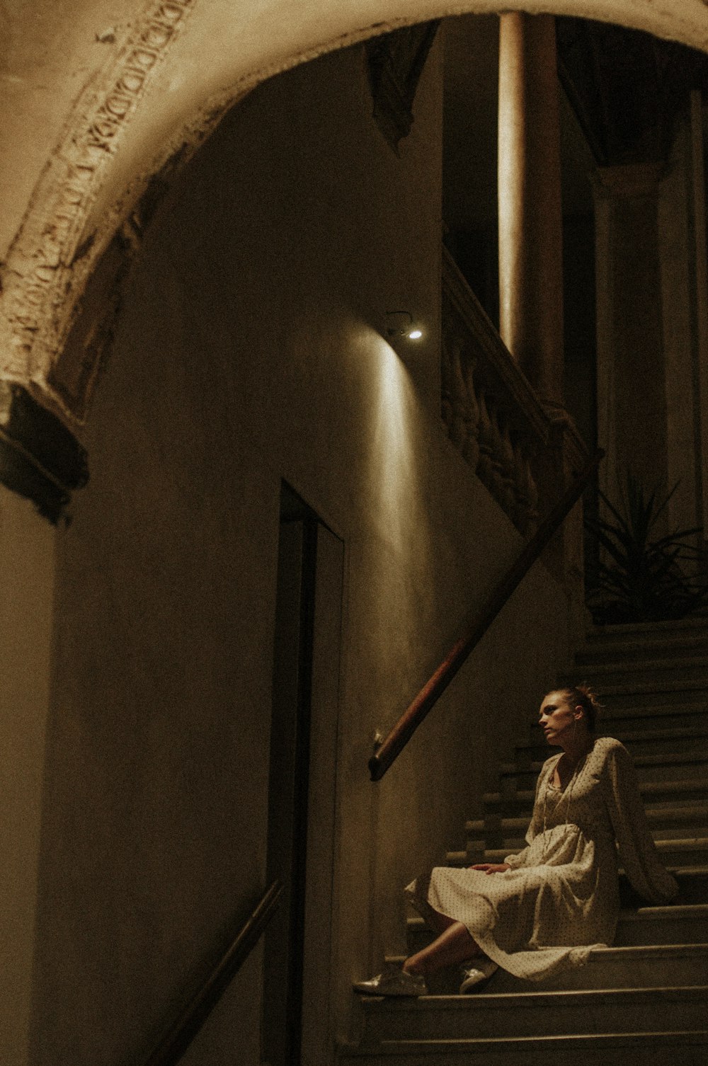 man in white and black stripe long sleeve shirt sitting on brown wooden staircase