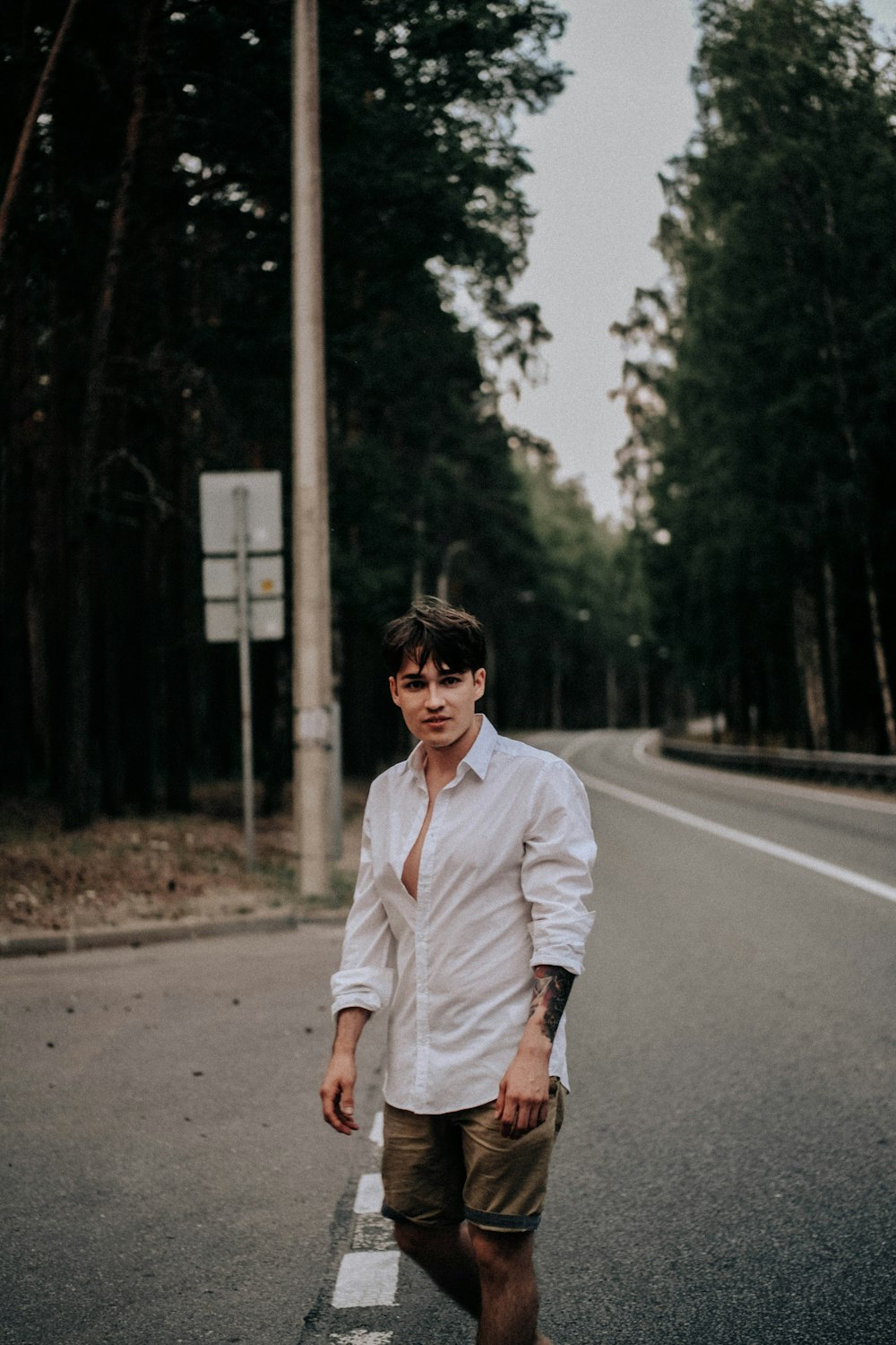 man in white dress shirt and brown pants standing on road during daytime