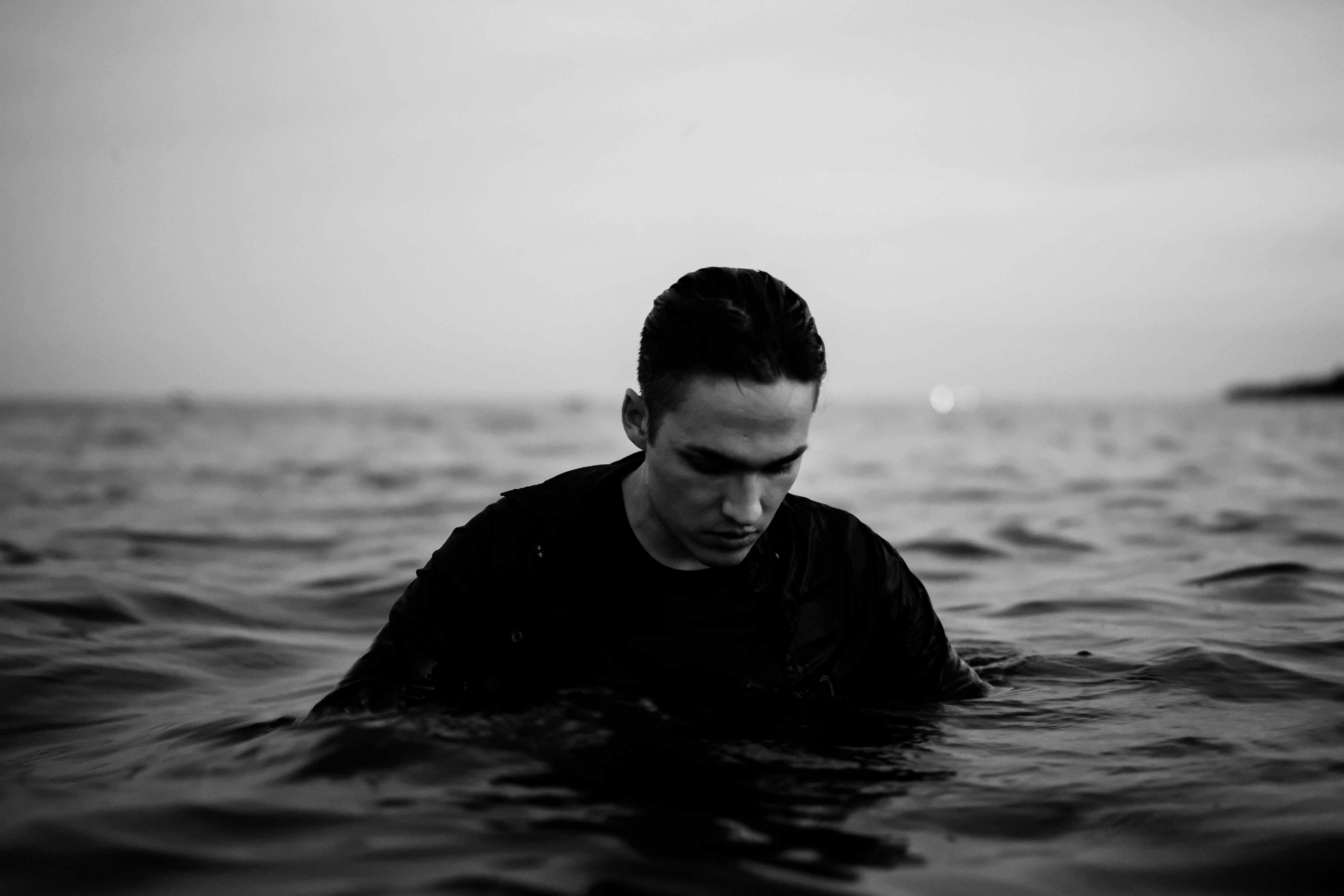 man in black long sleeve shirt in water in grayscale photography