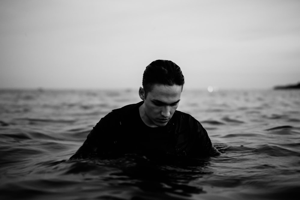 man in black long sleeve shirt in water in grayscale photography