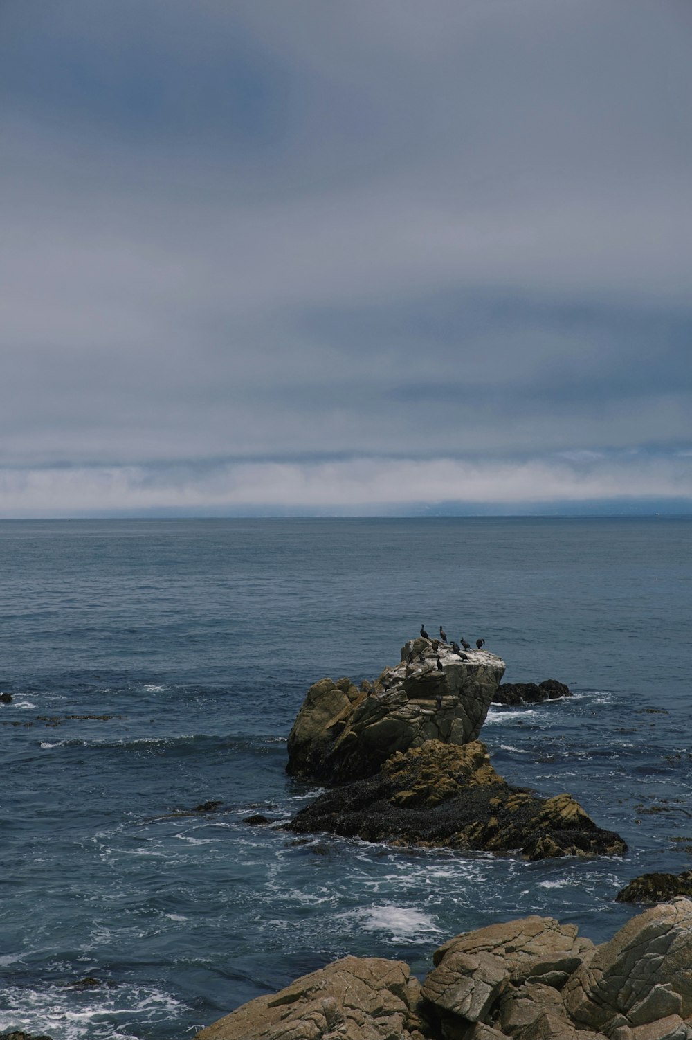 brown rock formation on sea under white clouds during daytime