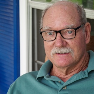 man in green polo shirt wearing black framed eyeglasses