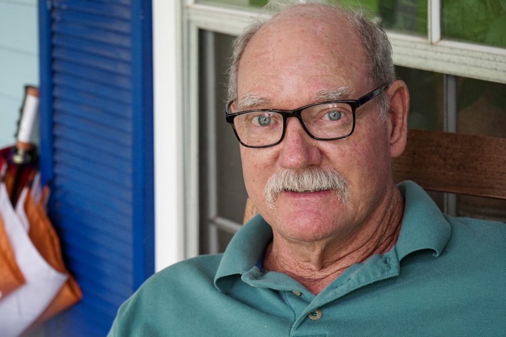 man in green polo shirt wearing black framed eyeglasses