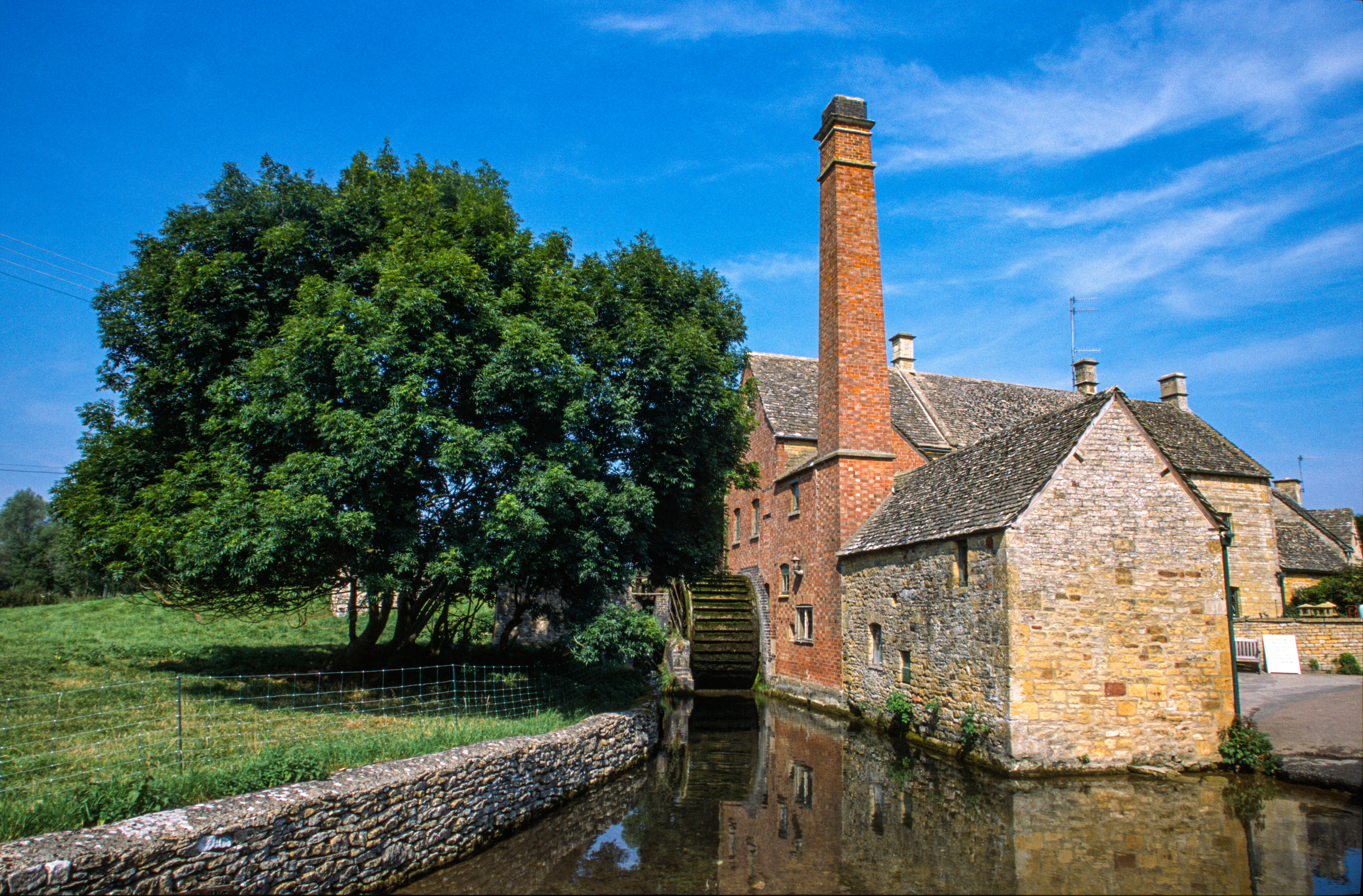 brown brick building near green trees and river during daytime