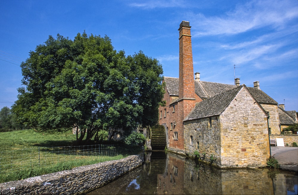 brown brick building near green trees and river during daytime