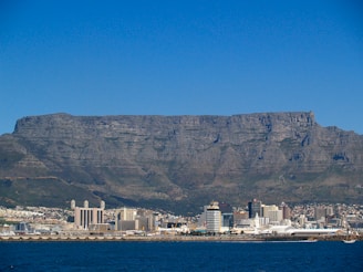 white and brown buildings on brown mountain near body of water during daytime