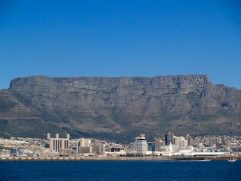 white and brown buildings on brown mountain near body of water during daytime