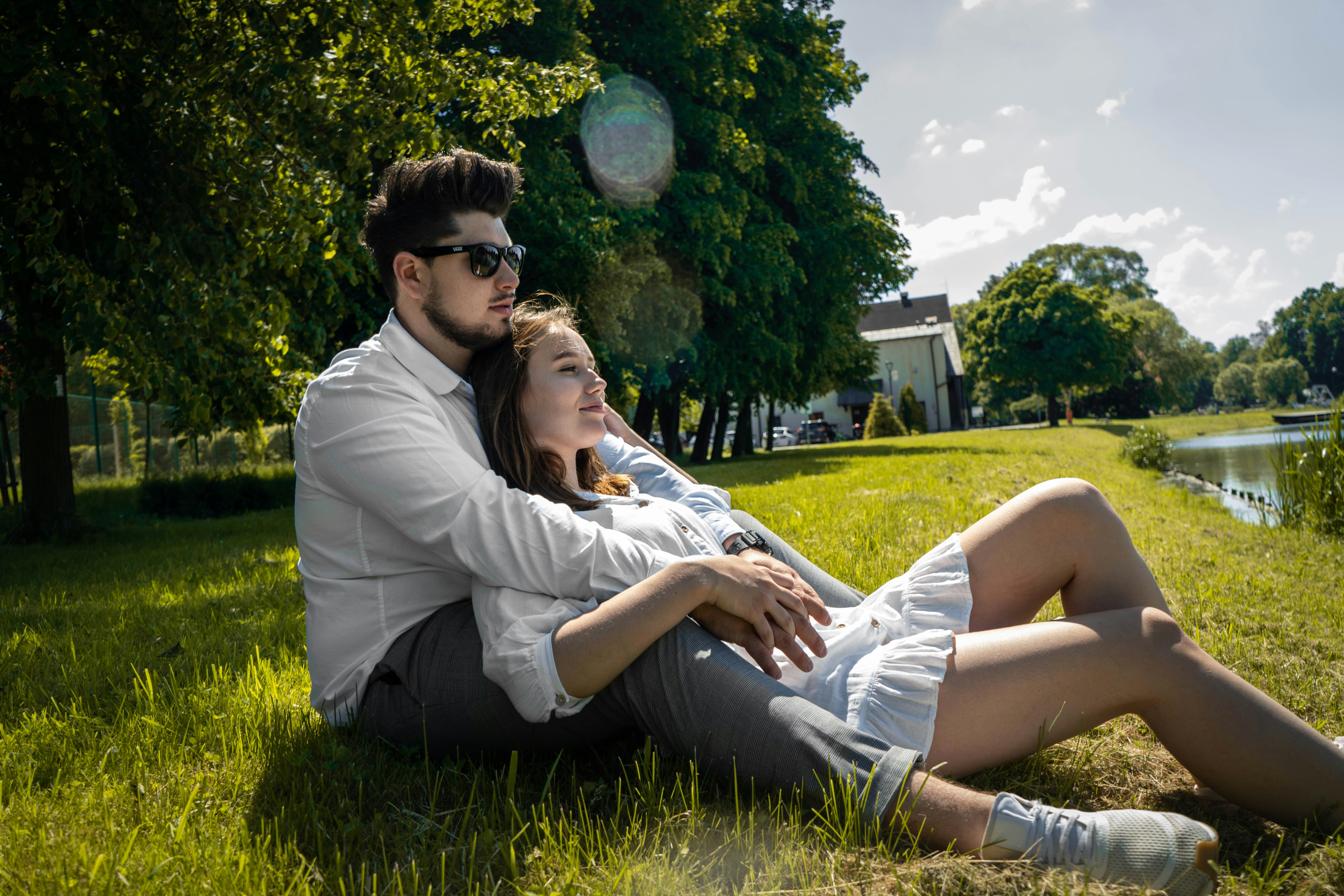 homme et femme assis sur le champ d’herbe verte pendant la journée