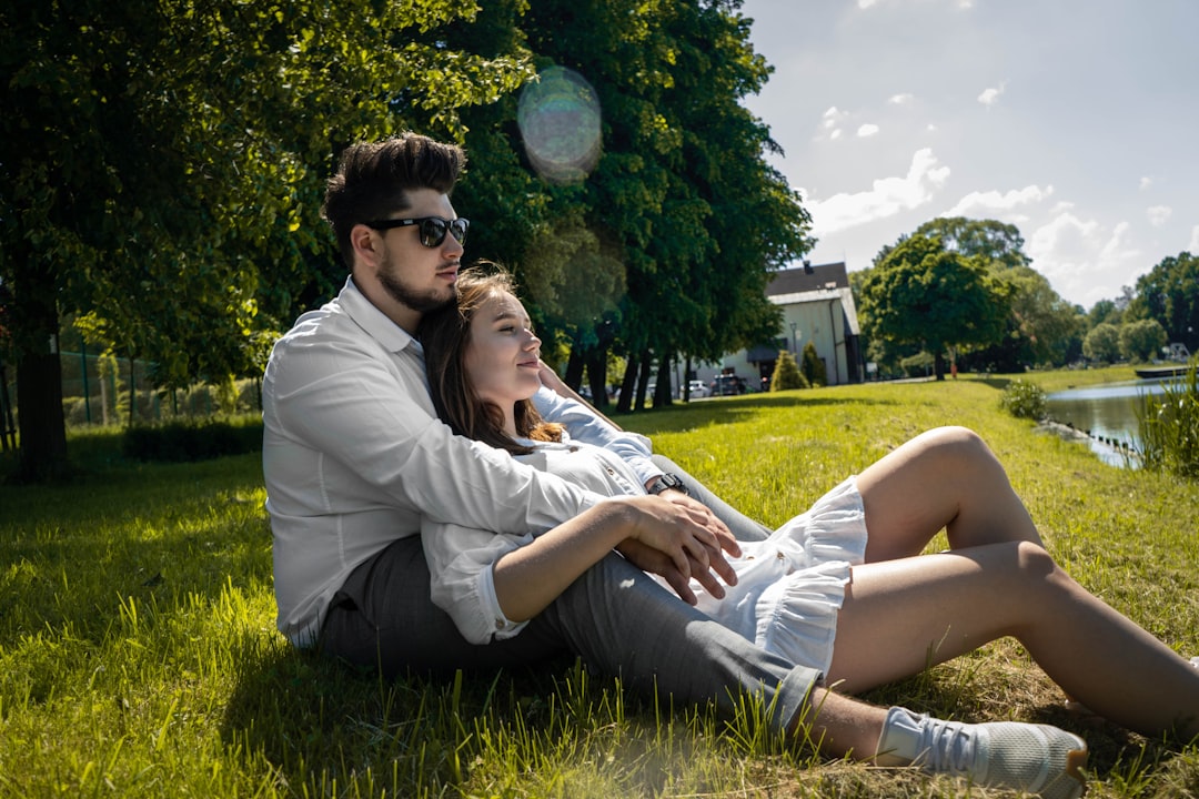 man and woman sitting on green grass field during daytime