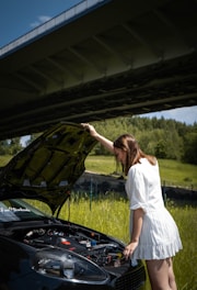 woman in white dress standing beside black car during daytime