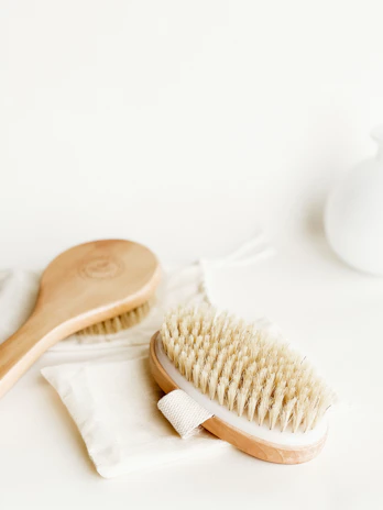 A close-up of premium natural wooden brushes arranged elegantly on a cream fabric background.