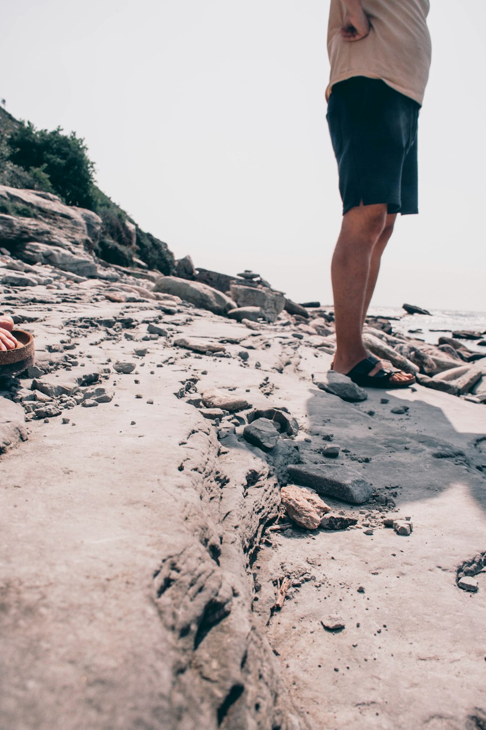 person in black shorts standing on rocky shore during daytime