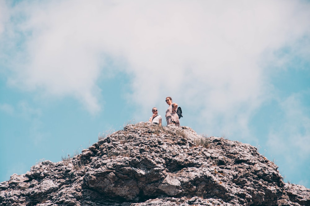 Mann in weißem Hemd und schwarzen Shorts, der tagsüber auf Felsen steht