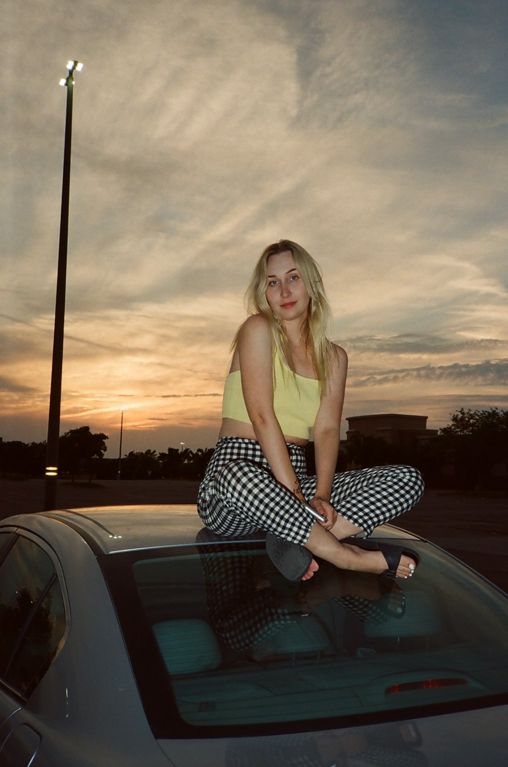 woman in brown tank top and black and white polka dot skirt standing on black car