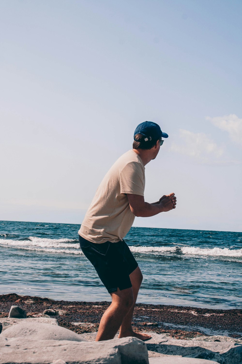 man in white t-shirt and black shorts standing on beach during daytime