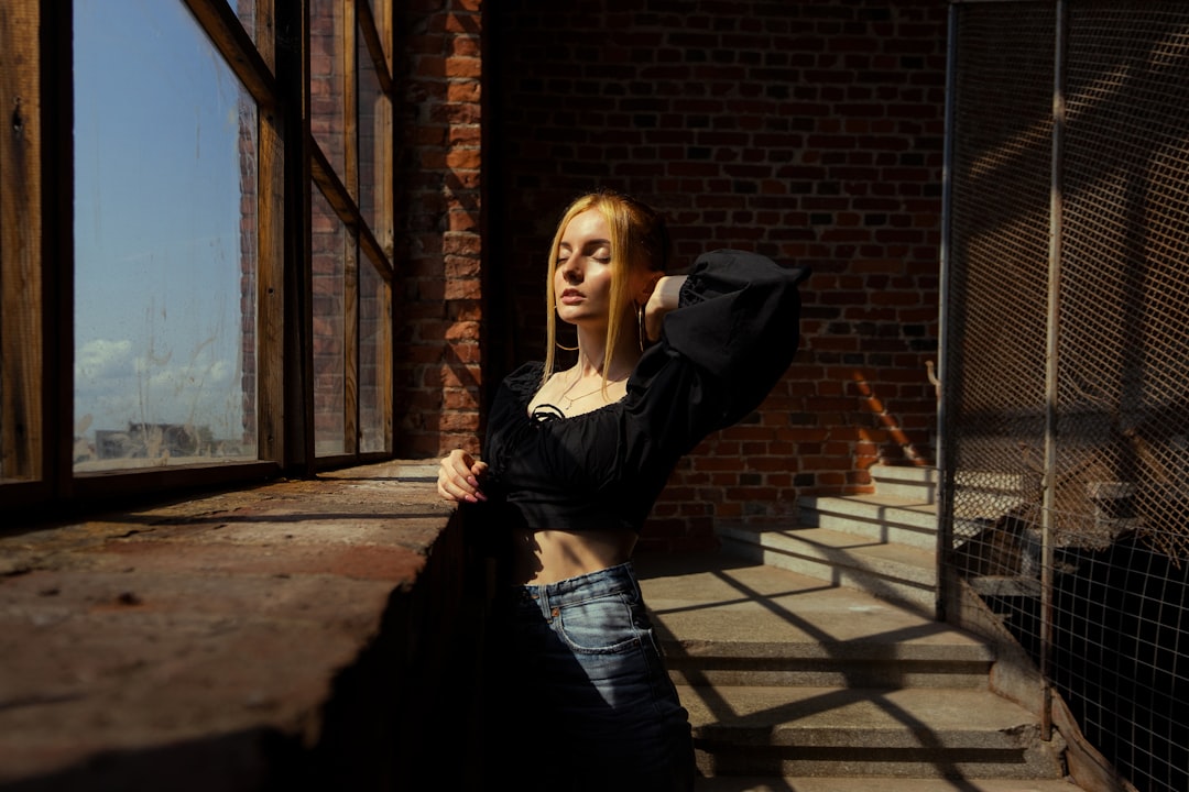woman in black long sleeve shirt and black skirt standing near brown brick wall during daytime