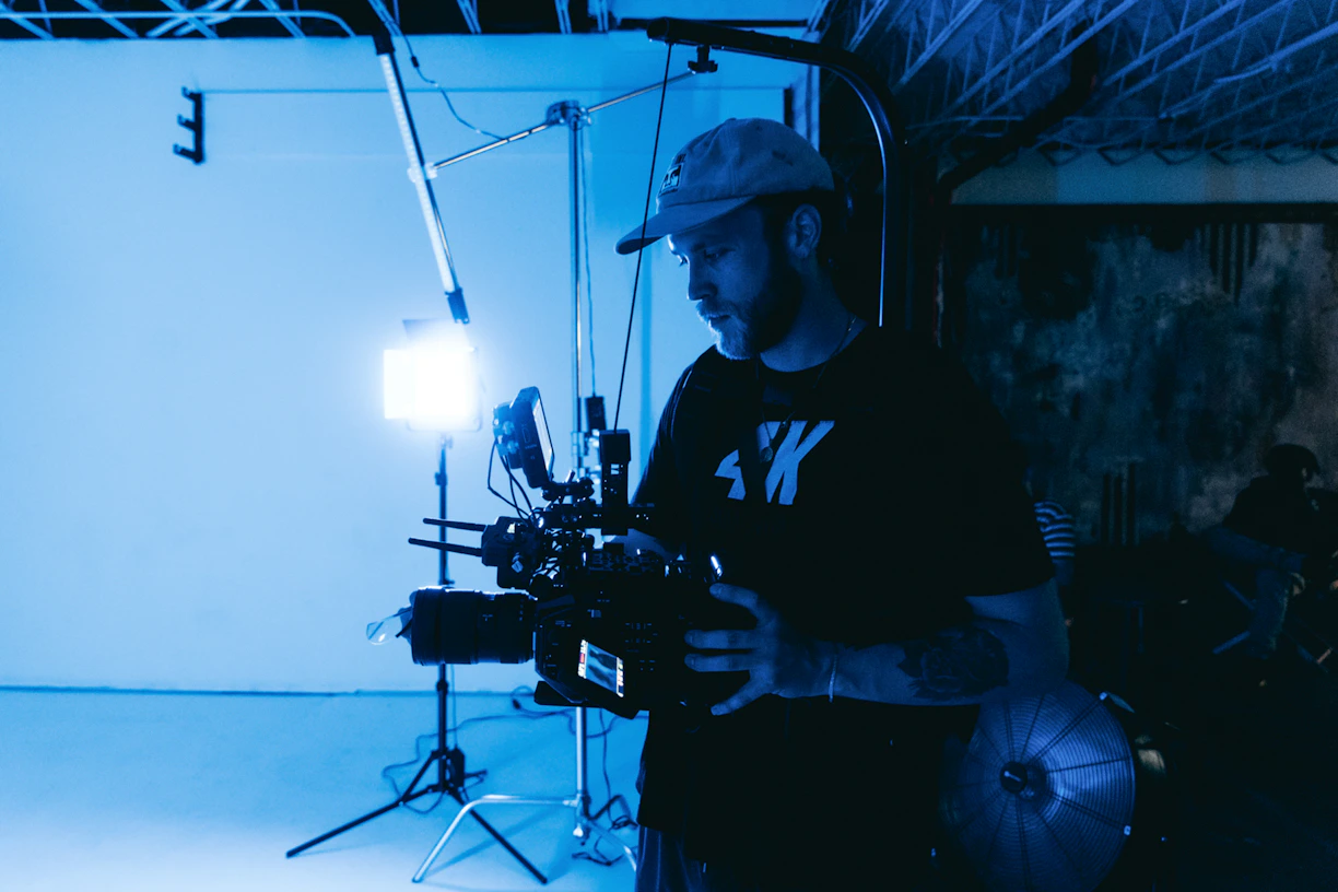 A candid portrait of a passionate freelance videomaker working with a camera in a cozy studio filled with warm light.