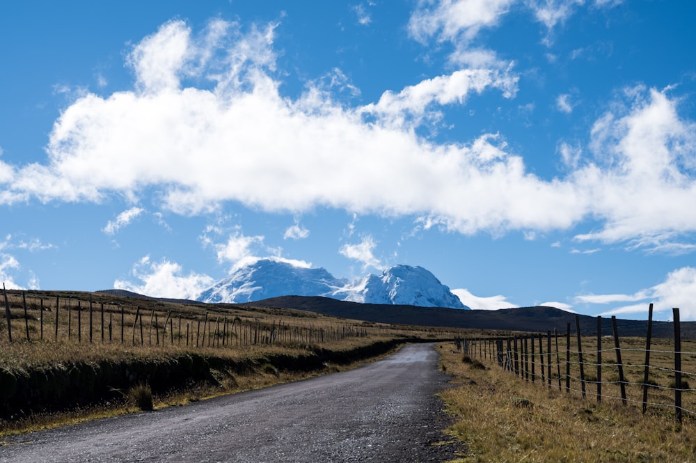 brown wooden fence on green grass field under blue sky and white clouds during daytime