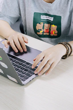 person using macbook pro on white table
