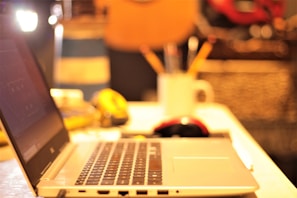 Open laptop with writing software and scattered notes in a warm room.