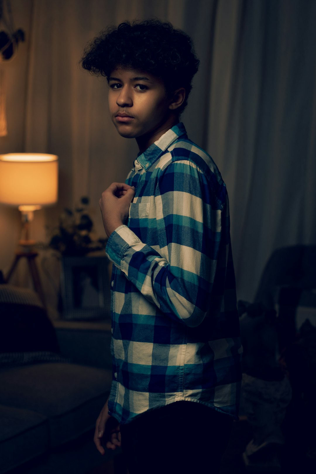 man in green white and black plaid dress shirt standing near table lamp