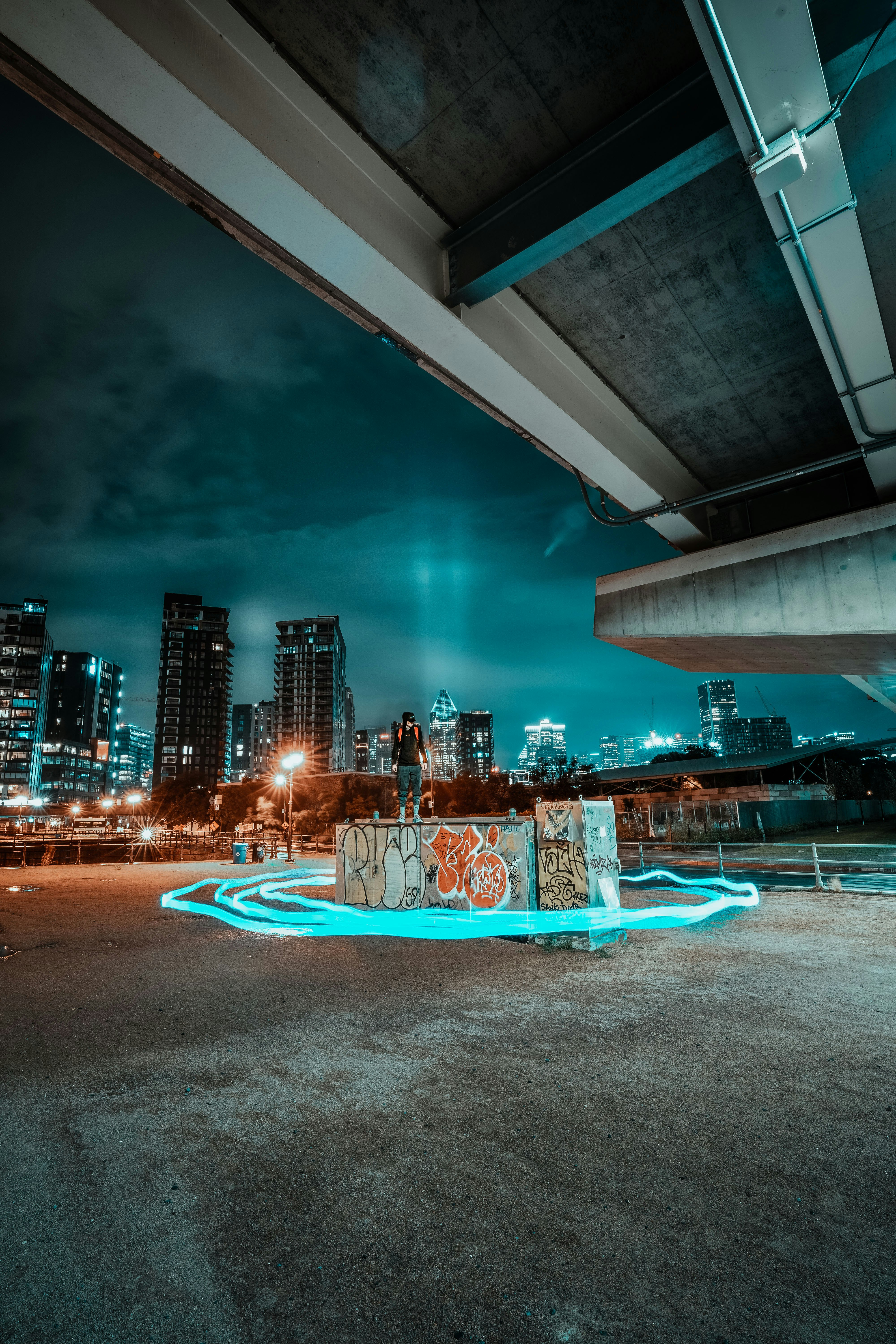 people in a park with a lighted city buildings in the distance during night time