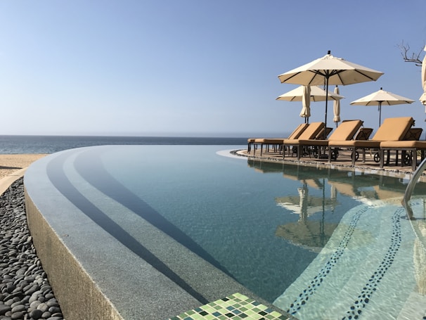 A tranquil infinity pool reflecting the clear blue sky and elegant lounge chairs