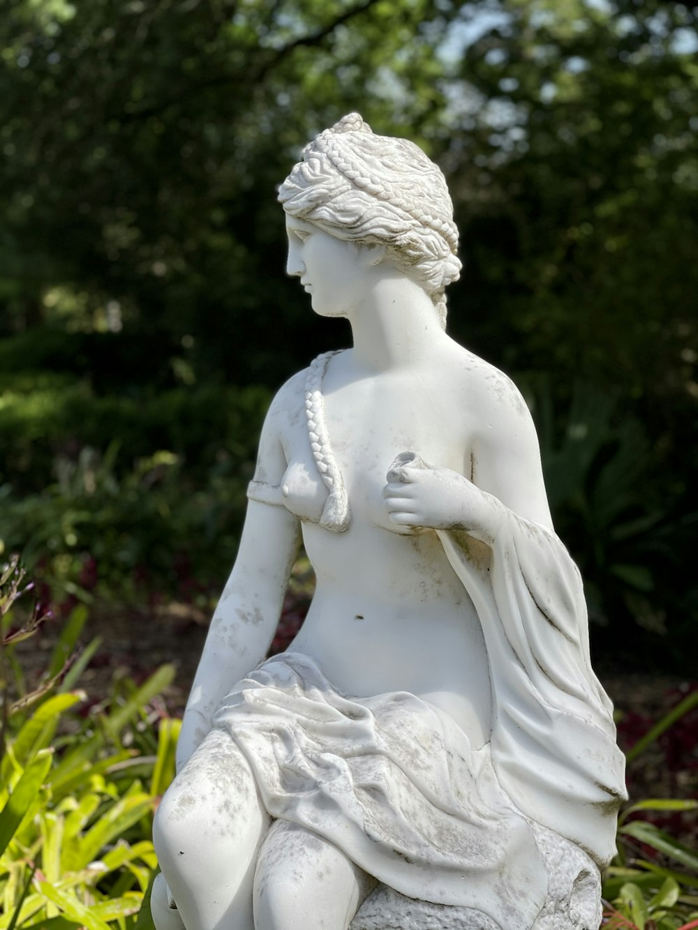 white angel statue near green plants during daytime