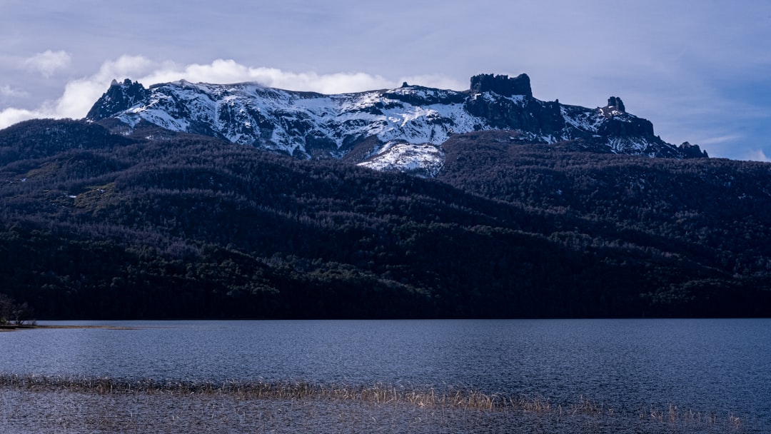 snow covered mountain near body of water during daytime