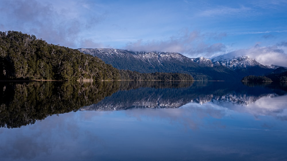 lago cerca de la montaña bajo nubes blancas durante el día