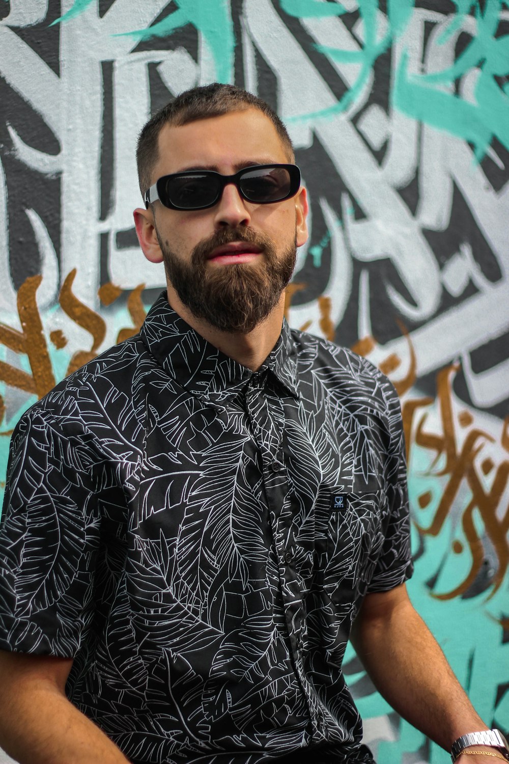 Hombre con camisa de botones florales en blanco y negro con gafas de sol negras