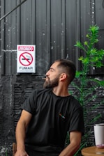 man in black crew neck t-shirt standing beside gray wall