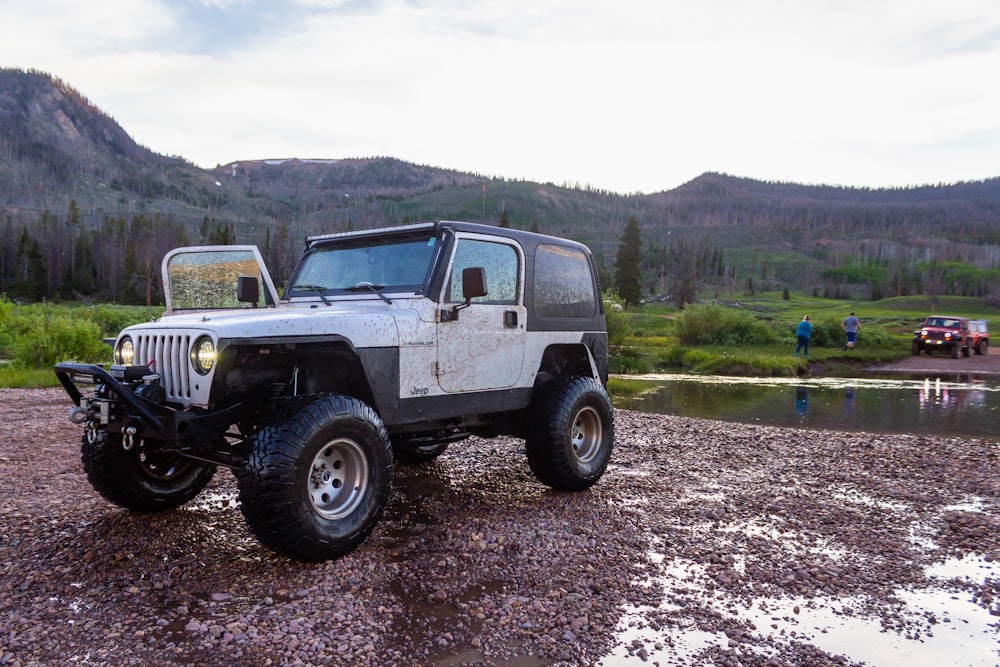 white and black jeep wrangler on dirt road during daytime