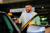 A valet attendant in uniform smiling while parking a car, with social media icons floating above.